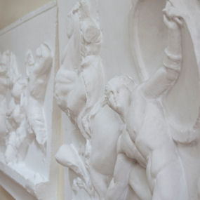 Wall sculpture of Greek gods, one holding up a shield 