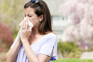 woman sneezing with tissue