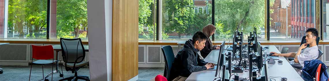 Students working at computer desks in a university study area.