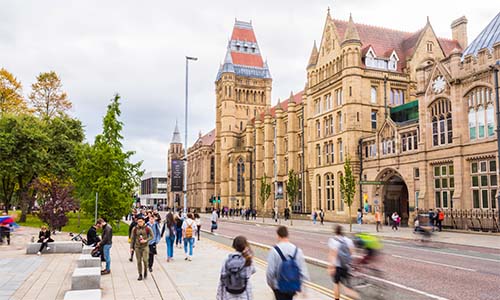 Street view of The University of Manchesrter from Oxford Road. Focus on Whitworth building with pedestrians in foreground.