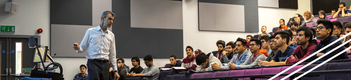 A lecture full of students with a lecturer presenting