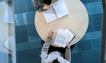 Two people talking at a desk as seen from above 