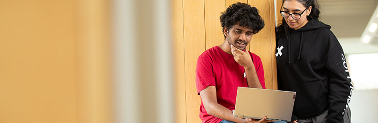 Students on the window ledge in AGLC looking at a laptop