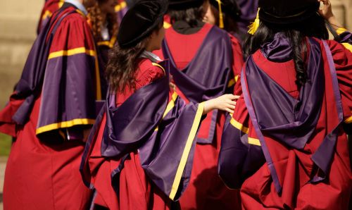 A crowd of PhD students in graduation robes seen from behind