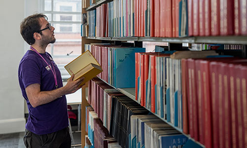 A member of Library staff shelving books