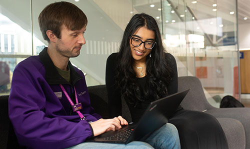 Member of staff helping a student with a laptop