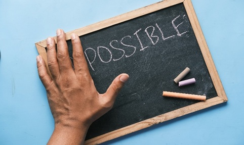 hand holding a chalk b.oard with possible written on it
