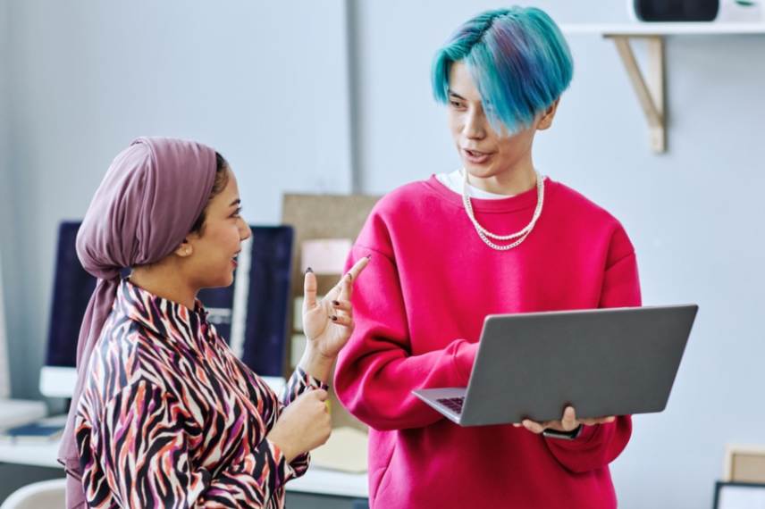 Two people talking in front of a laptop