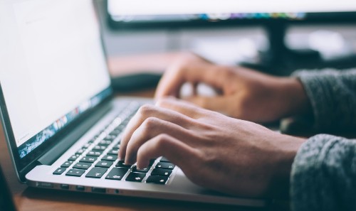 Hands typing on a laptop