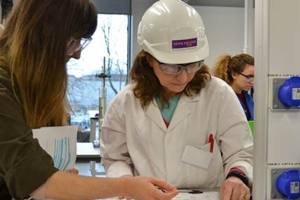 Two women working in a lab wearing PPE.