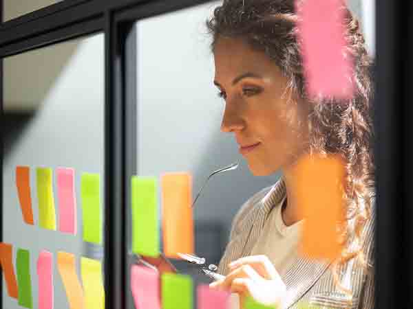 Woman looking at glass door with postit notes laid across the glass 