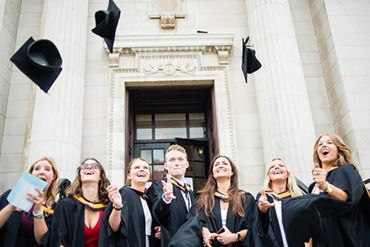 Students in academic gowns throwing their mortar boards into the air