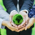 People joining hands holding a green earth 