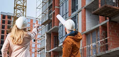 Two people looking at a building under construction.