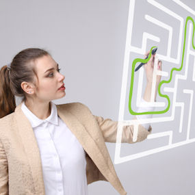 A woman draws into a maze diagram which appears suspended in the air 