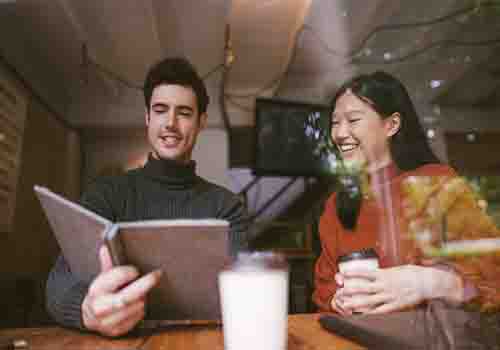 Man and women talking over a drink and looking at a book