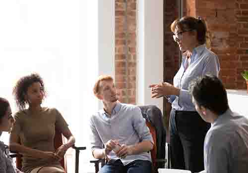 Women stood addressing at group of colleagues