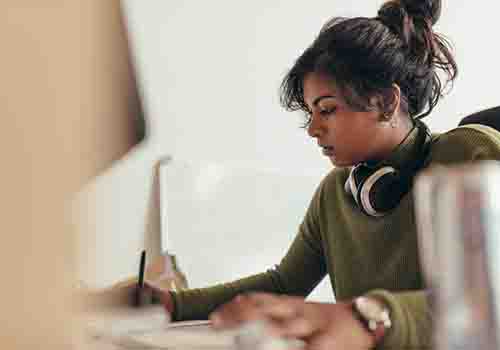 Women working at computer with headphone around her neck