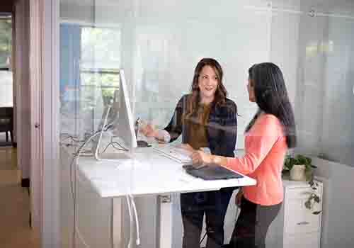 Two women talking at a standing desk