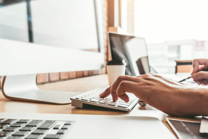 Person working on a computer and making notes