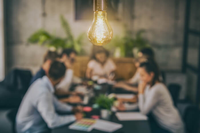 Team meeting with a lightbulb glowing above the table