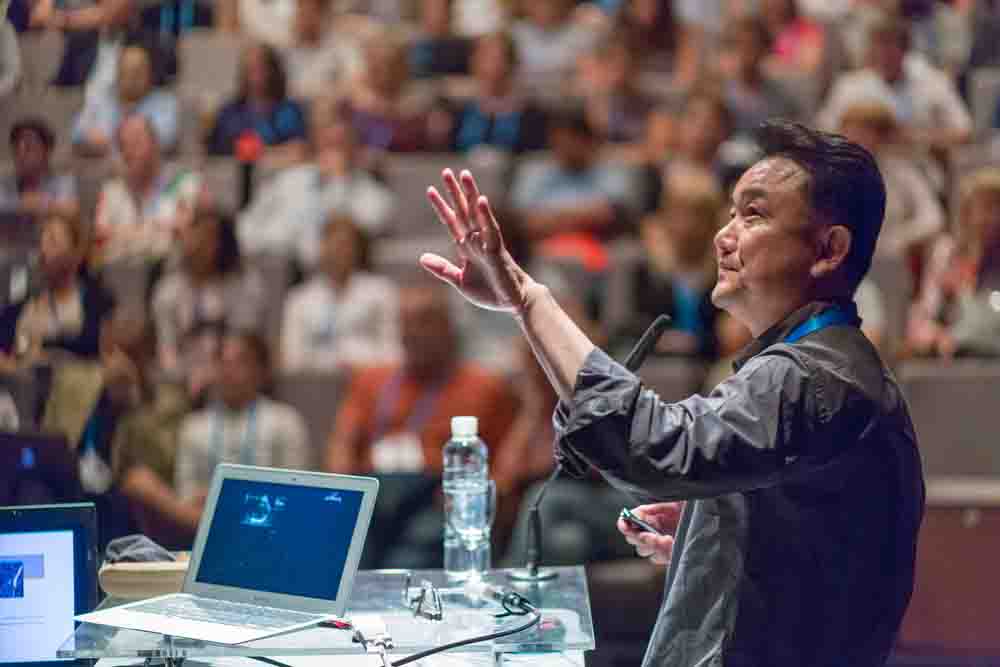 Man delivering a lecture to a full lecture hall