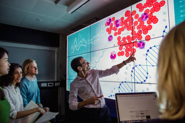 Man pointing to a display screen, with a group of people looking at the analysis.