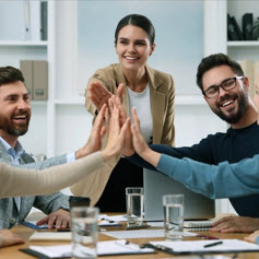 Team of employees joining hands in office