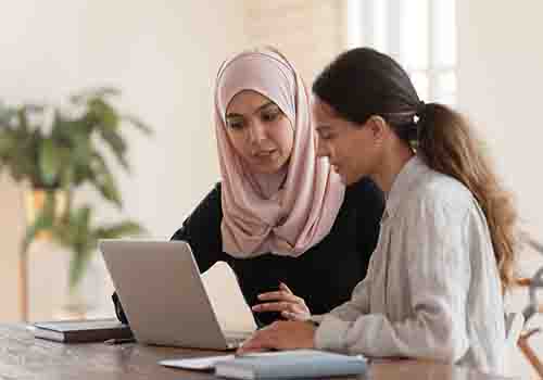 Two women working at a laptop together