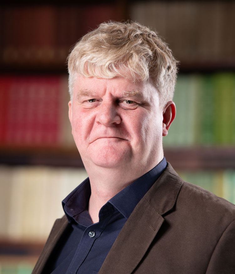 University of Manchester academic man standing in front of bookcase 
