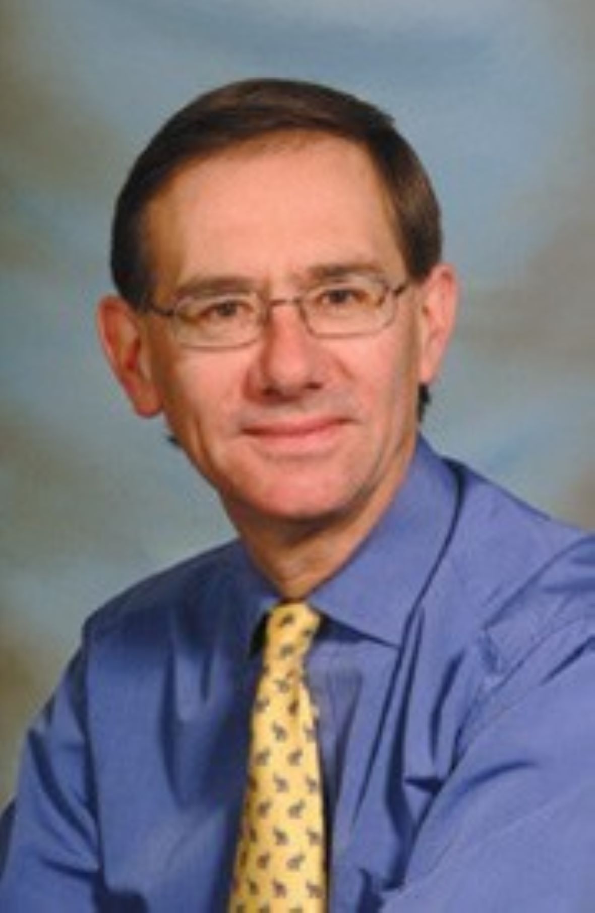 Photograph of Professor Iain Mackie smiling in front of a blue backdrop