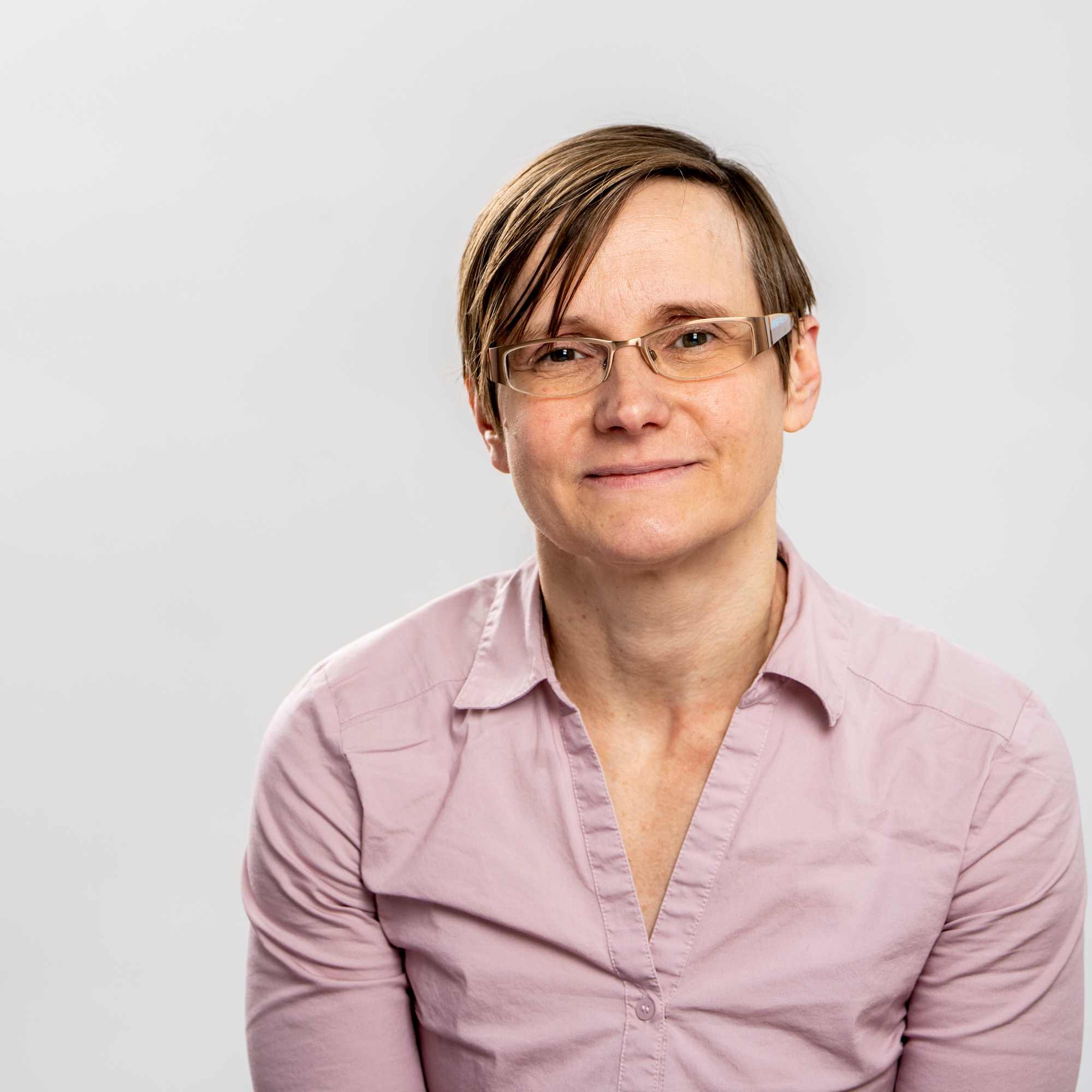 Photograph of Jenny Silverthorne smiling in front of a pale grey background