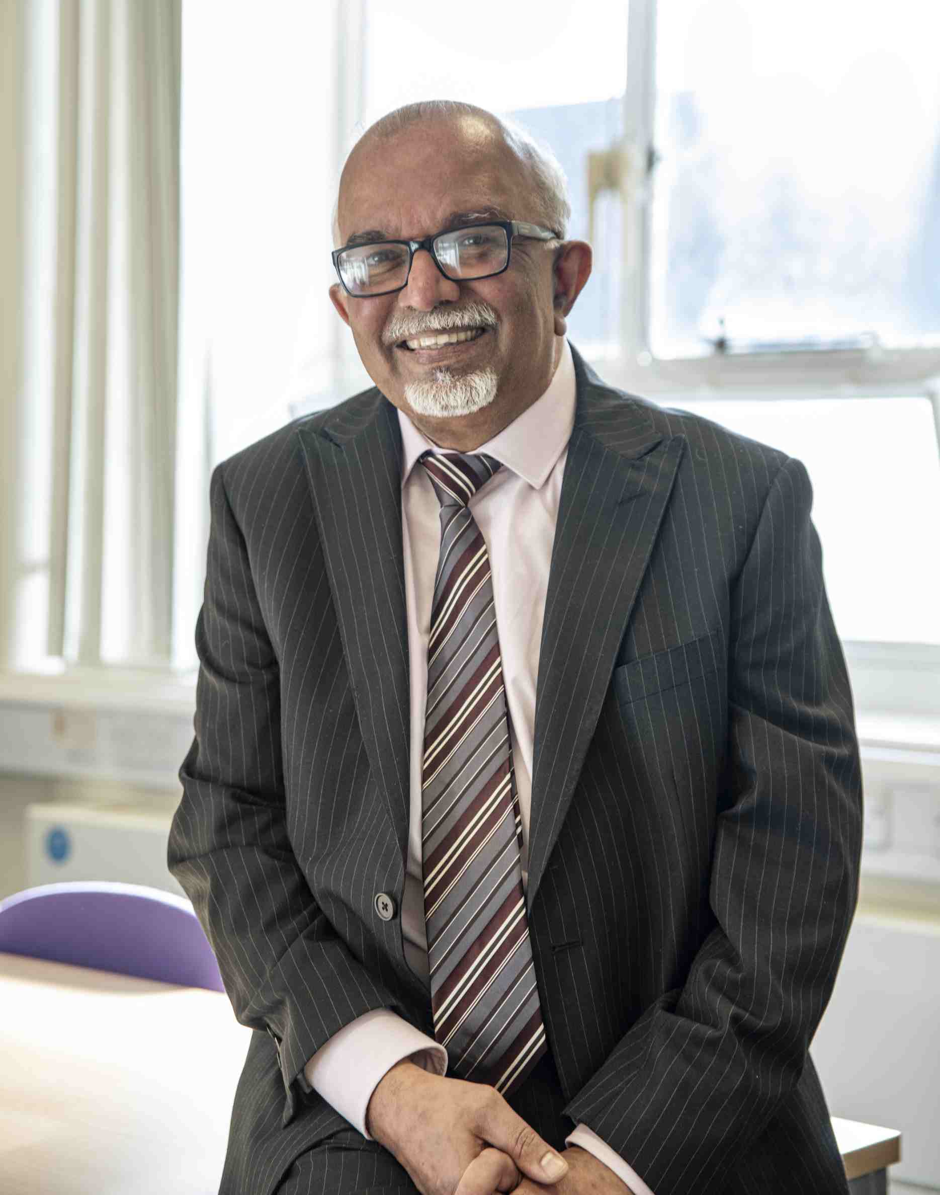 Photograph of Professor Raj Ariyaratnam smiling in front of a sunny window. 