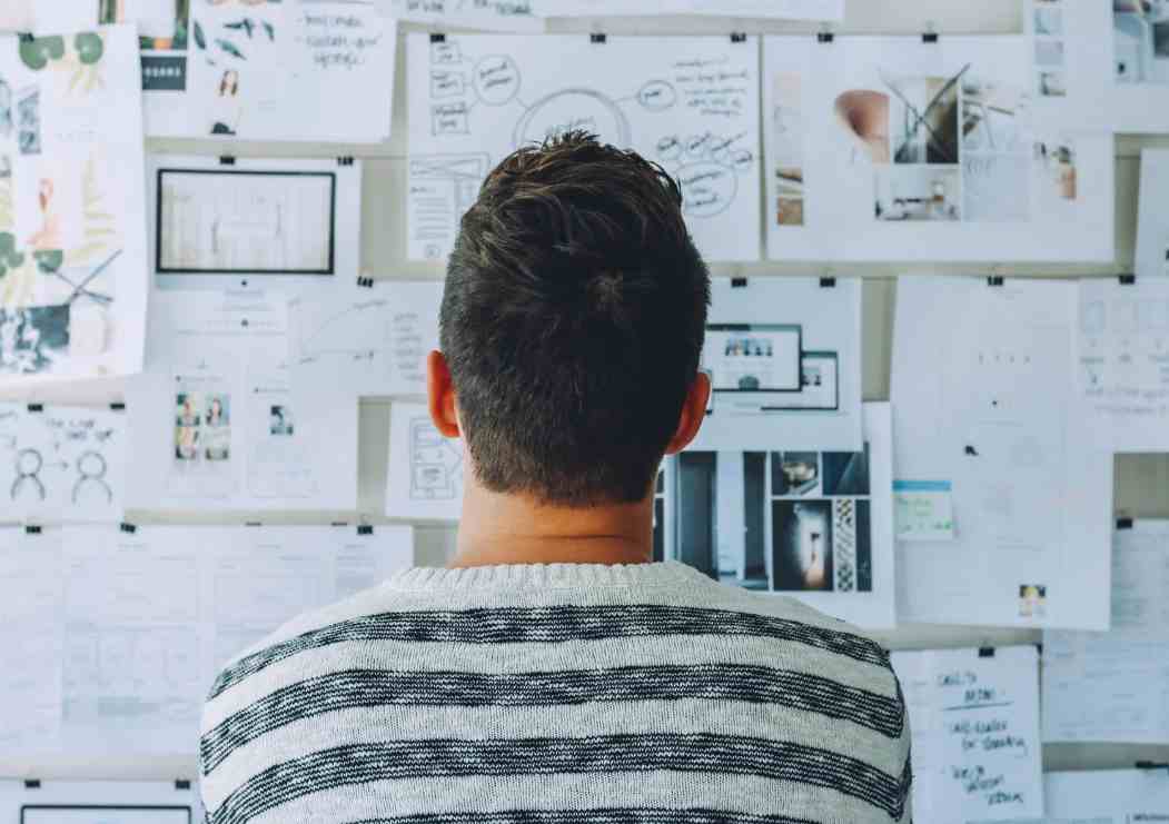 A man looking at a board with lots of notes