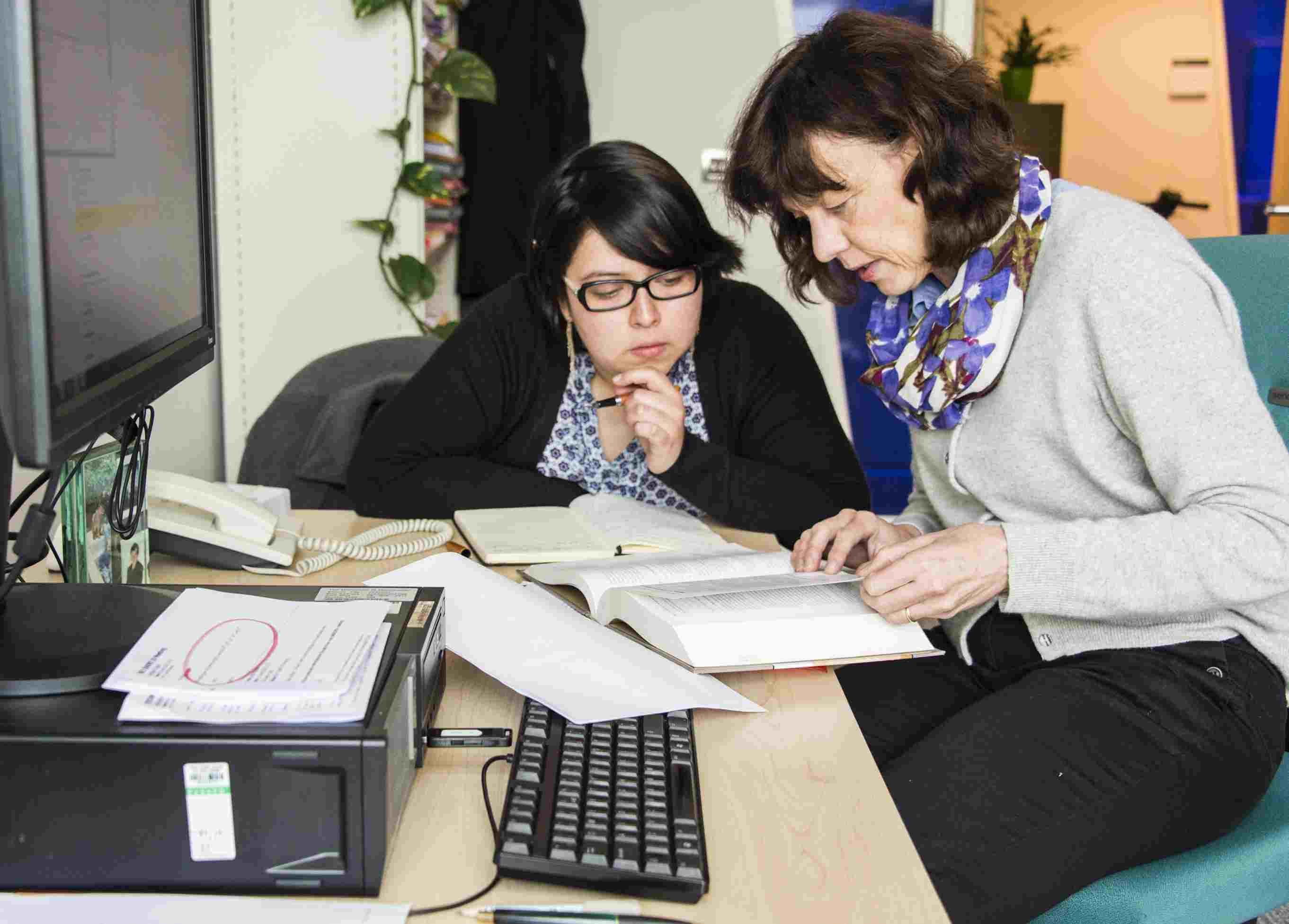 Advisor and student looking over papers together while seated at a desk